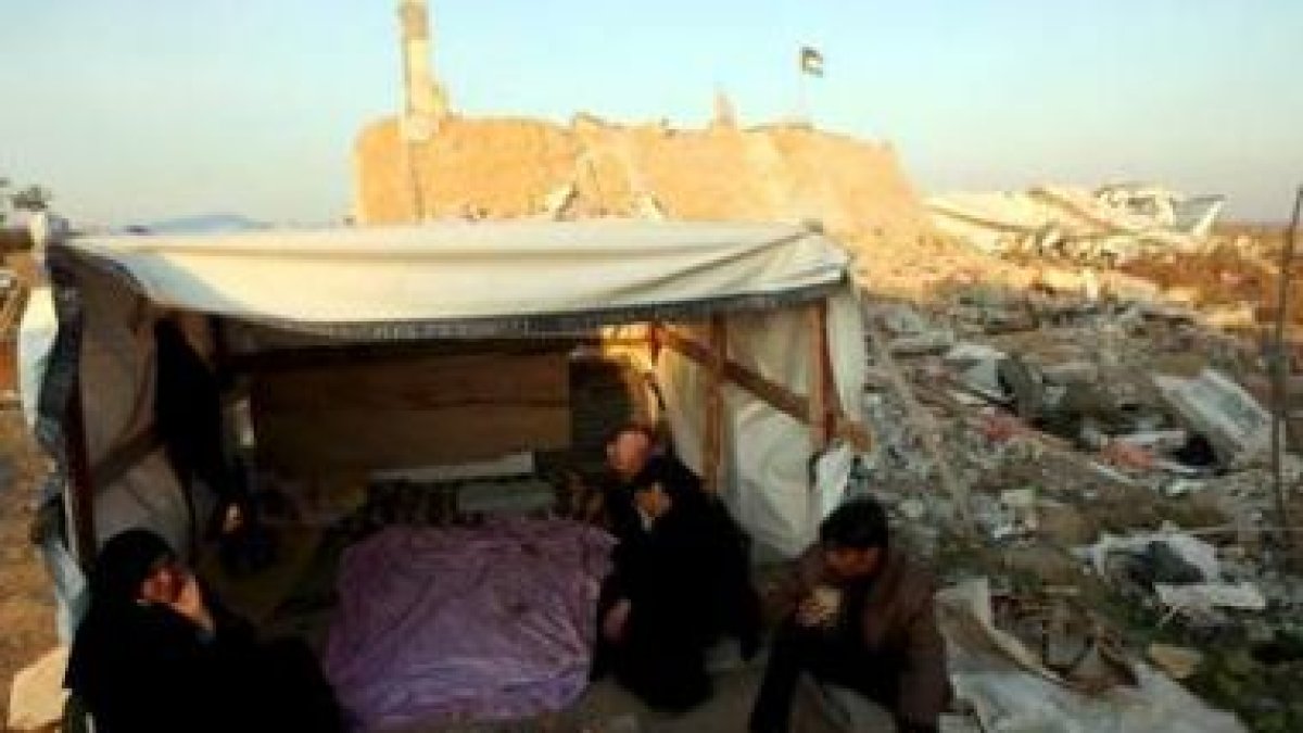 Una familia palestina vive en una caseta entre los restos de su casa destruida en un campo de refugi