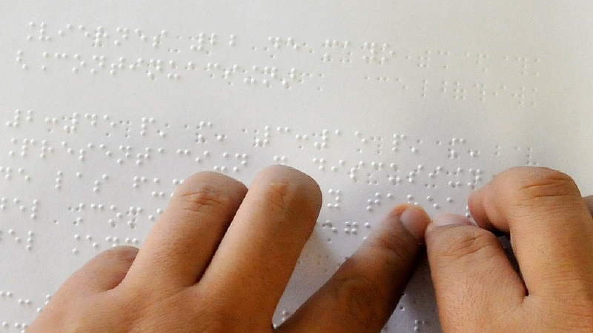 Una persona ciega lee un texto en braille gracias a la ayuda de las manos.
