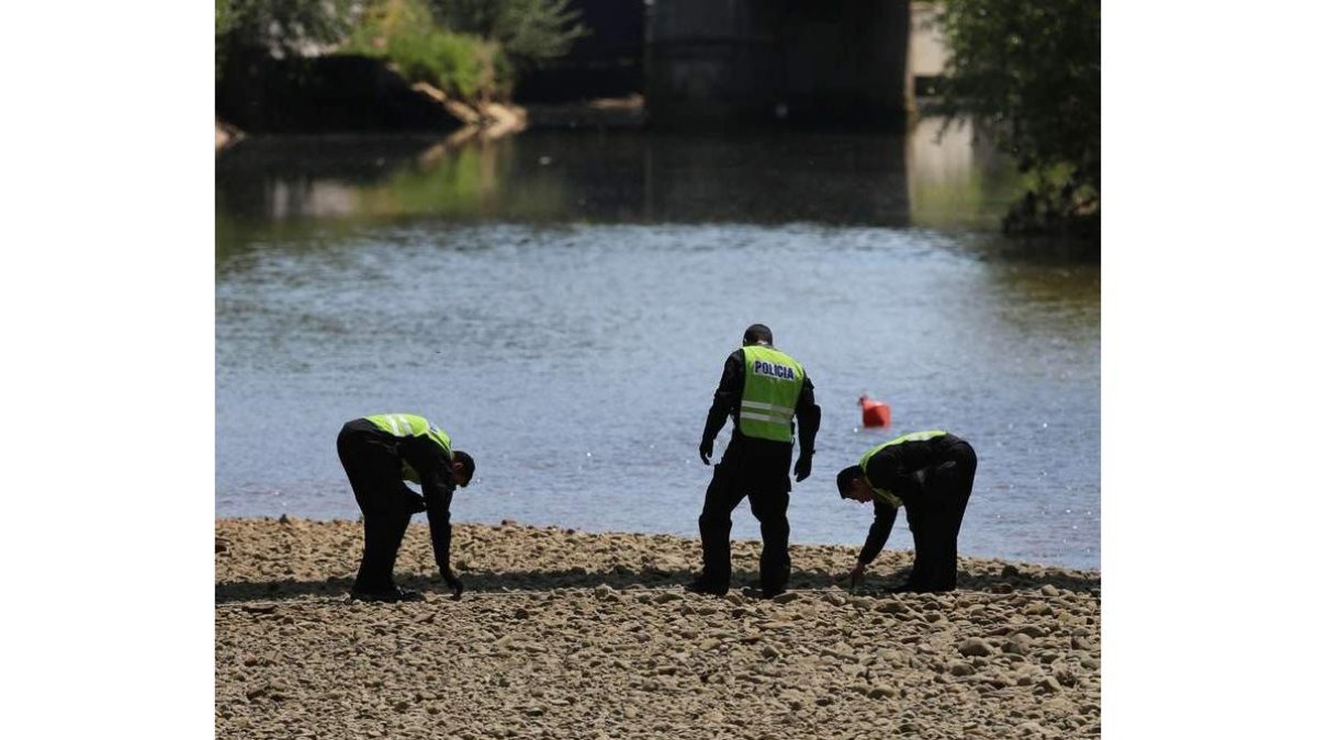 Agentes de la policía, buscando el arma en el río.