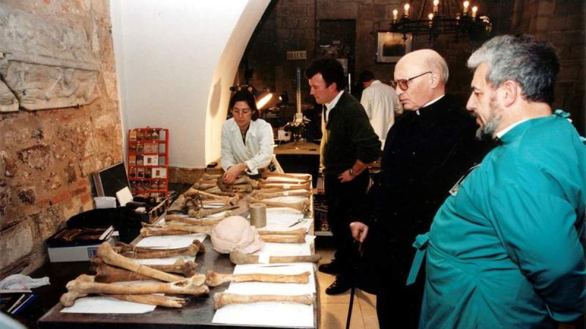 Imagen del abad Viñayo con tres de los investigadores del proyecto científico y ante parte de los restos óseos hallados. NORBERTO