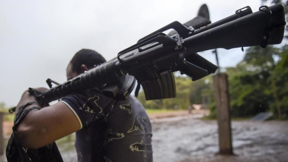 Un miembro de las FARC entrega un fusil de asalto.