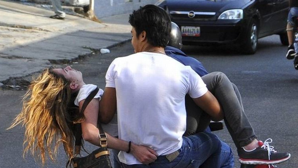 Génesis Carmona, evacuada en una moto tras ser tiroteada en la protesta de este martes en Valencia (Venezuela).