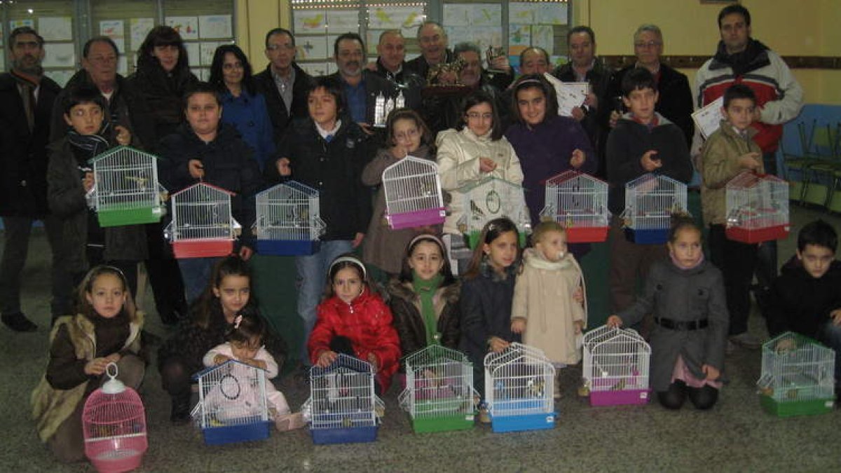 Los ganadores del concurso ornitológico posan con los niños premiados en el certamen de dibujo, que recibieron un canario.