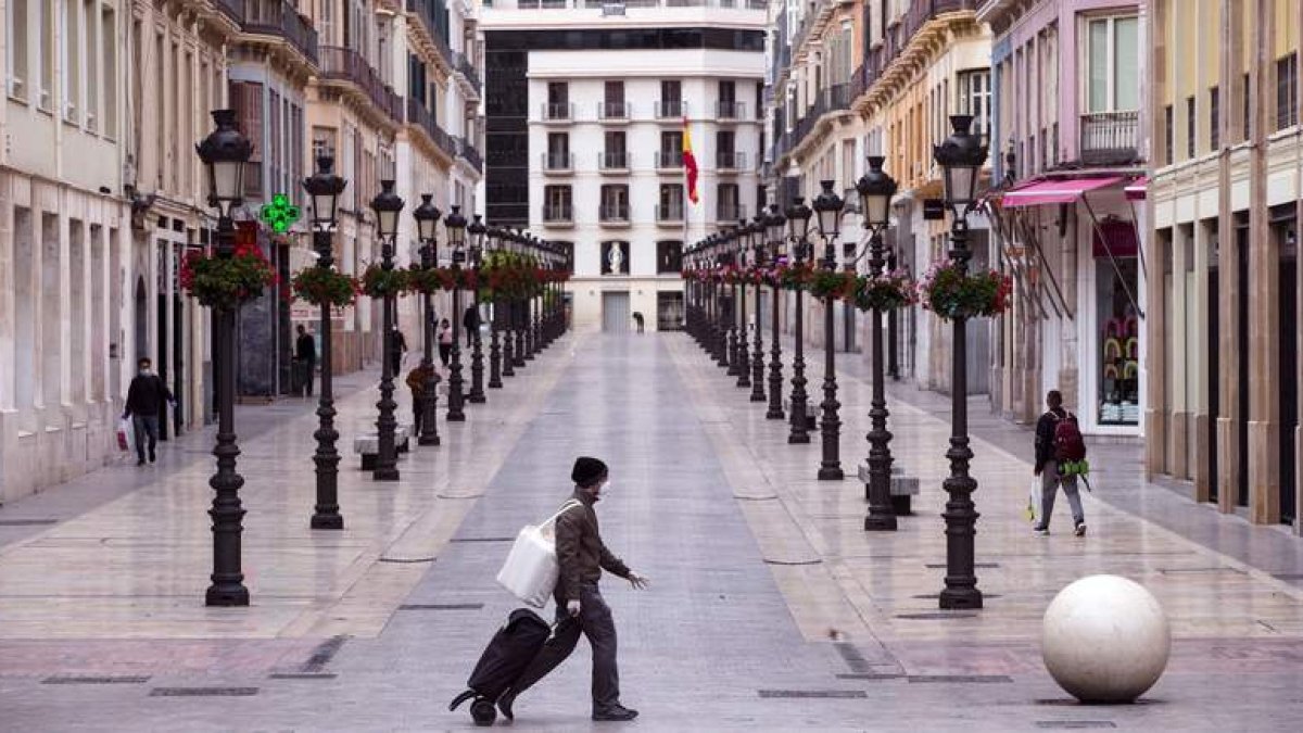 Sólo algunos viandantes cruzan por las calles de una Málaga vacía.