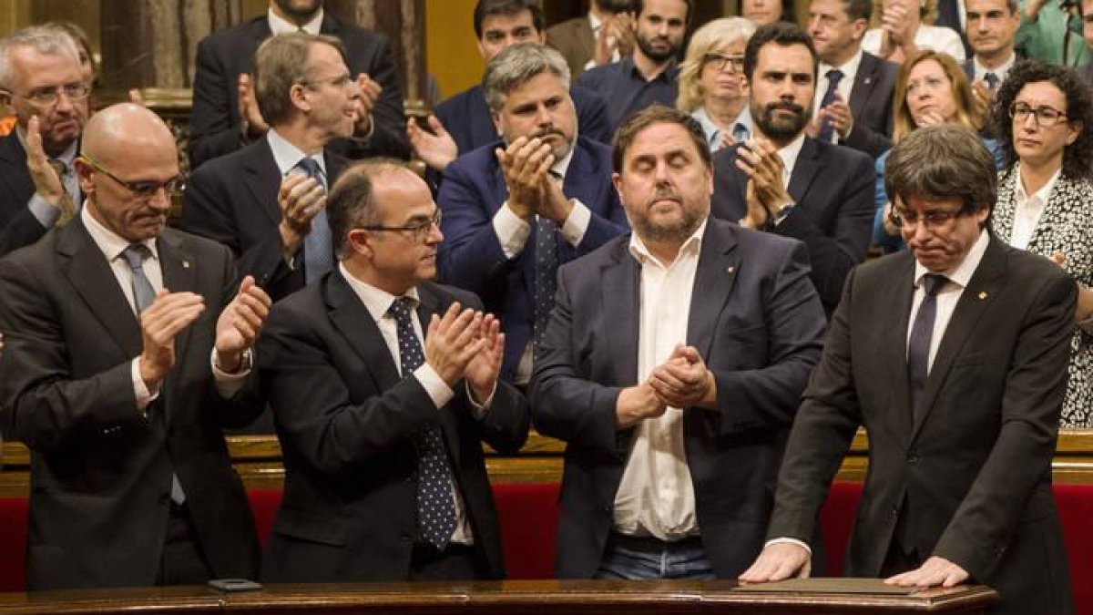 El presidente de la Generalitat, Carles Puigdemont (d), con Junqueras a su lado, recibe el aplauso de los miembros del del Govern.