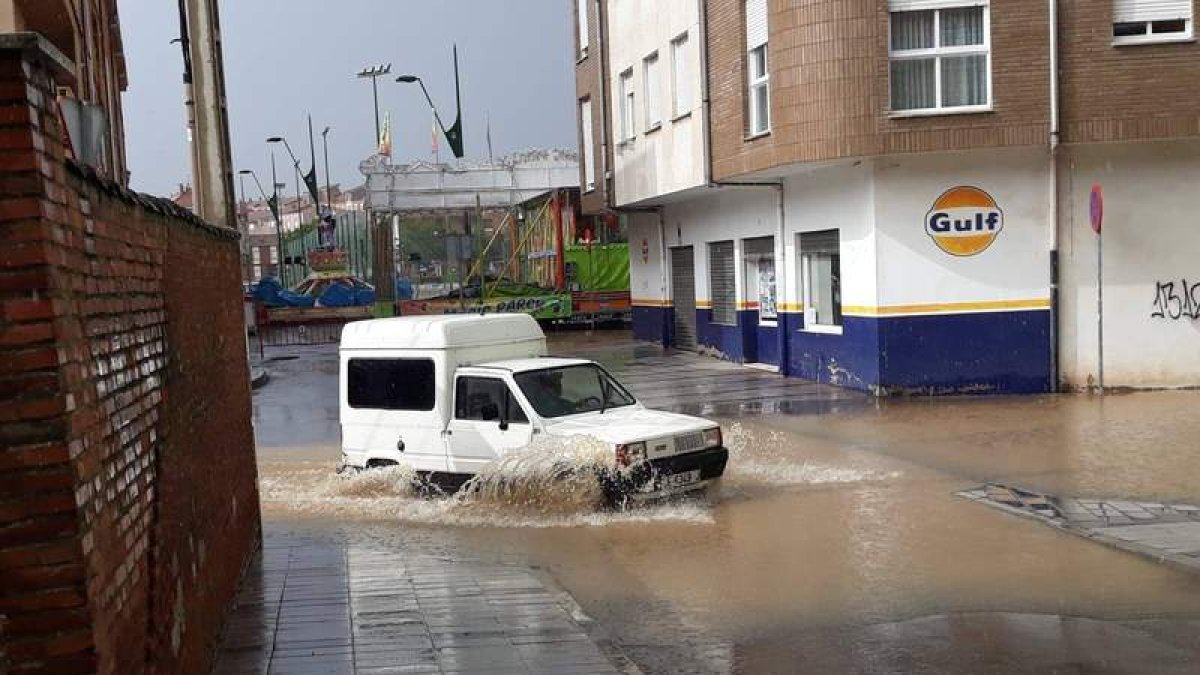 Un coche transita por las calles cercanas al parque de la Era ayer por la tarde, donde las alcantarillas no pudieron asumir el agua caída. DL