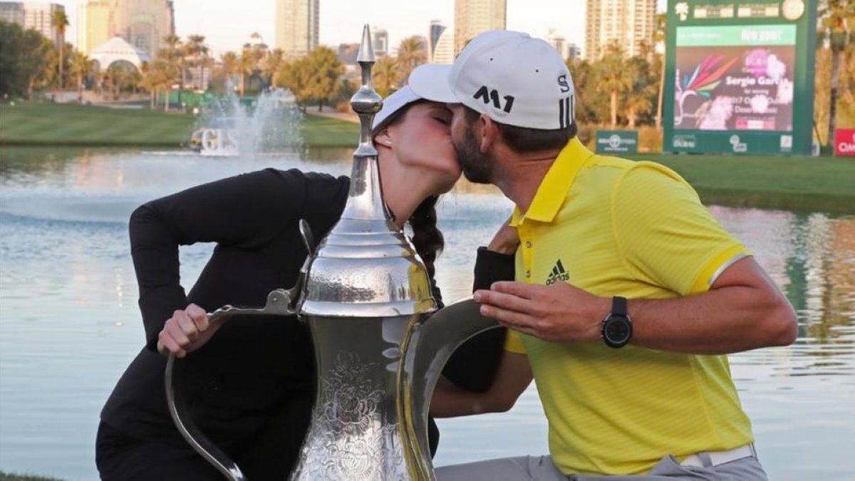 Sergio García besa a su novia, Angela Ankins, junto al trofeo del Omega Dubai Desert Classic.