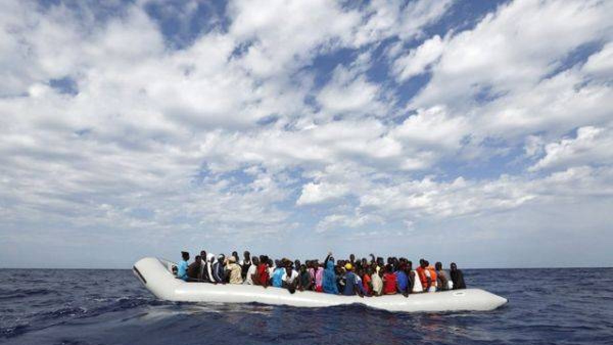 Refugiados a borde de un cayuco frente a la costa de Lampedusa, en Italia.