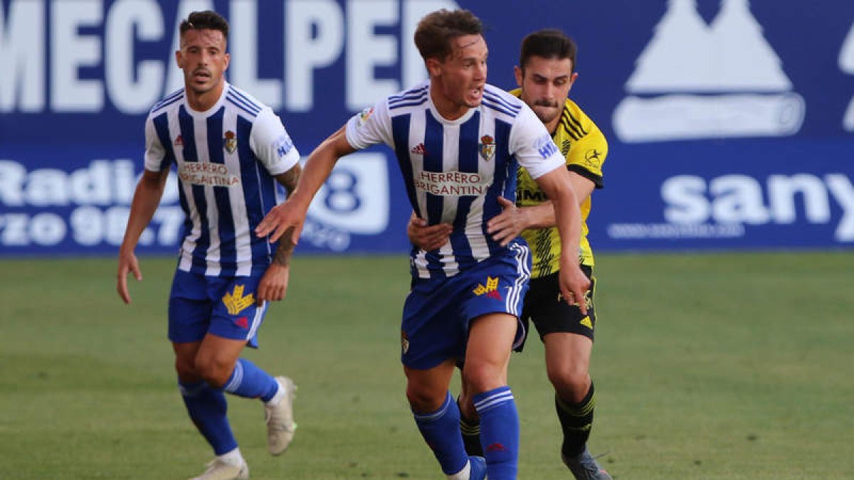 Gianfranco Gazzaniga se lleva el balón a pesar del agarrón sufrido por parte de un jugador del equipo ovetense. L. DE LA MATA