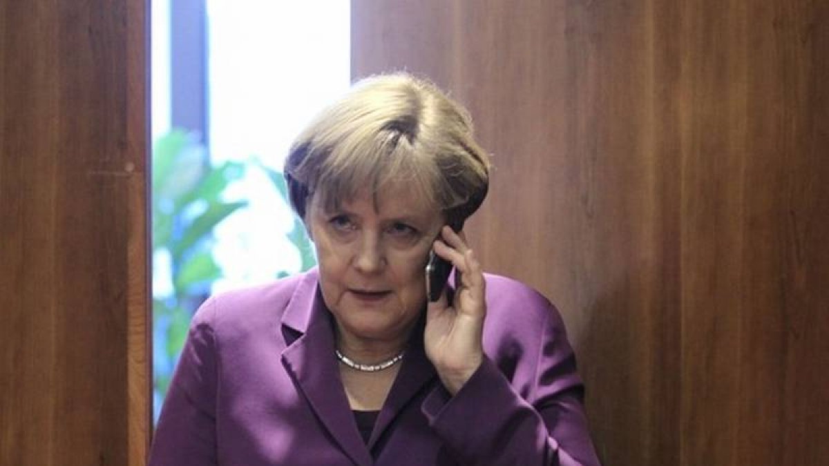 Angela Merkel despacha con su móvil.