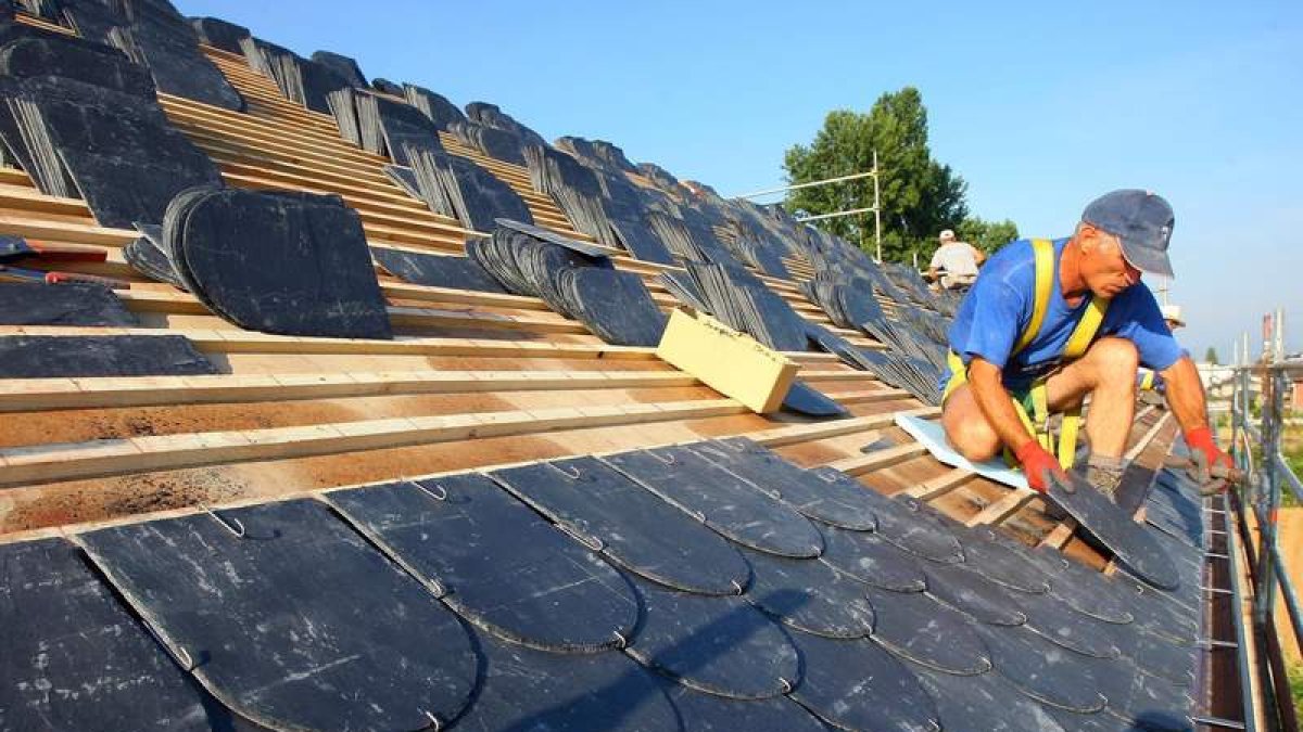 Un trabajador instala un tejado de pizarra en Ponferrada.