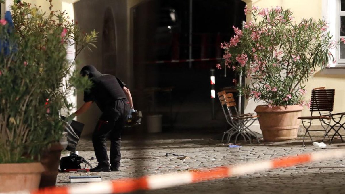 Un agente examina la mochila en la que el autor del ataque llevaba los explosivos, frente a un restaurante de Ansbach (Alemania), este domingo.