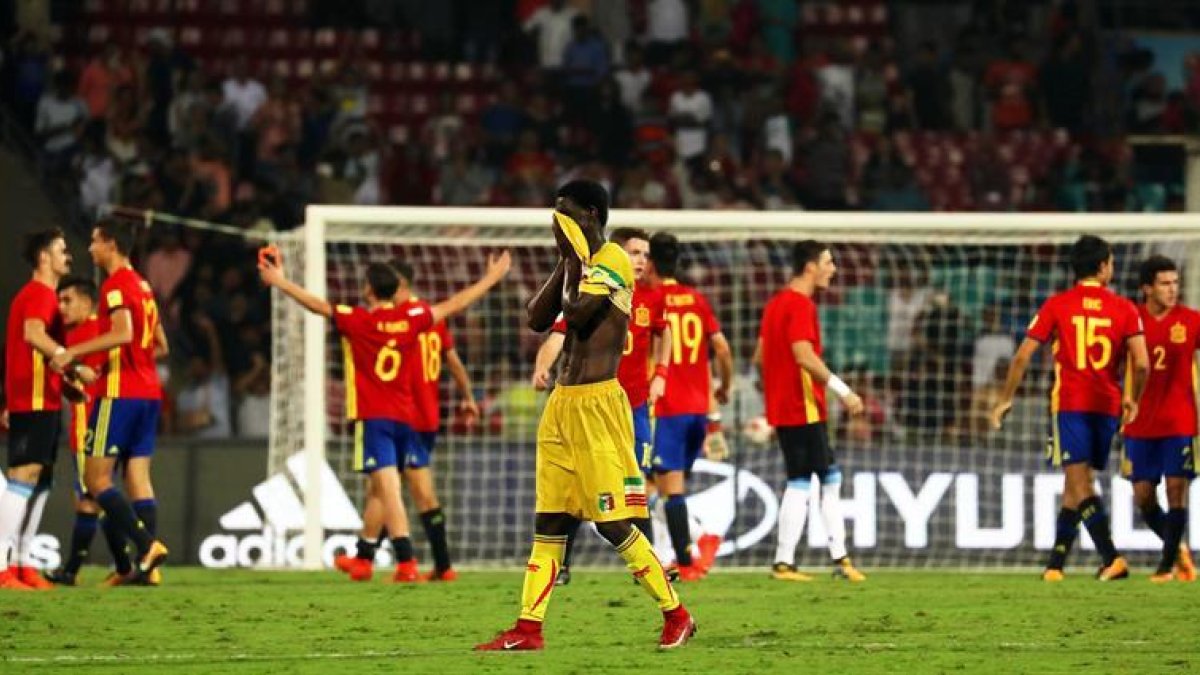 El ghanés Boubacar Haidara (c) reacciona mientras los jugadores de la selección española celebran tras vencer 3-1 a Mali en las semifinales del Mundial sub17 en el D Y Patil Stadium en Bombai, India.
