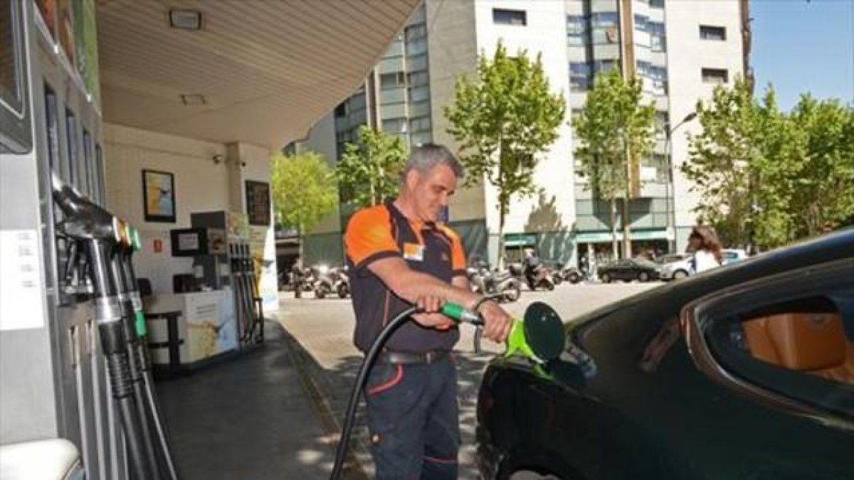 Un empleado llena un depósito en una gasolinera de Barcelona.
