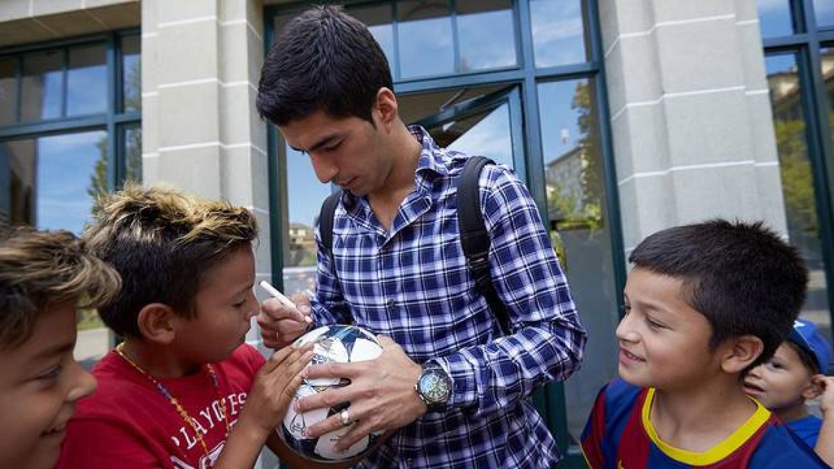 Luis Suárez firma unos balones a unos niños tras declarar ante el TAS, en Lausana.