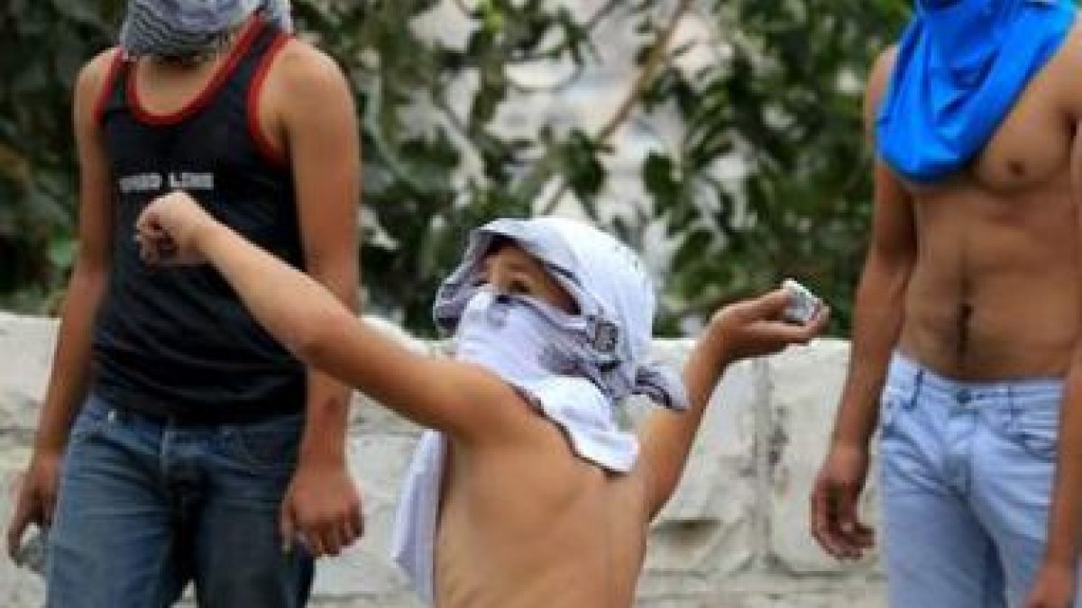 Un joven palestino lanza una piedra contra los antidisturbios israelíes en la Explanada de las Mezqu