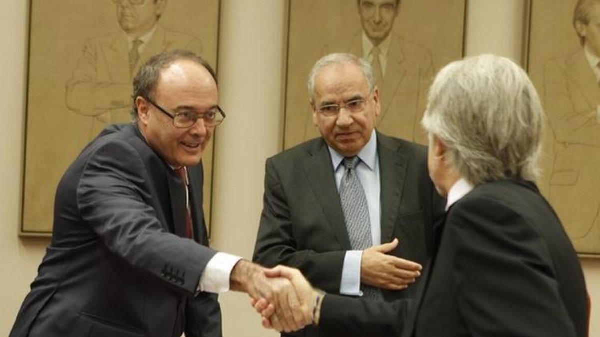 Luis María Linde saluda a Josep Sánchez Llibre delante de Alfonso Guerra, en la Comisión de Presupuestos.
