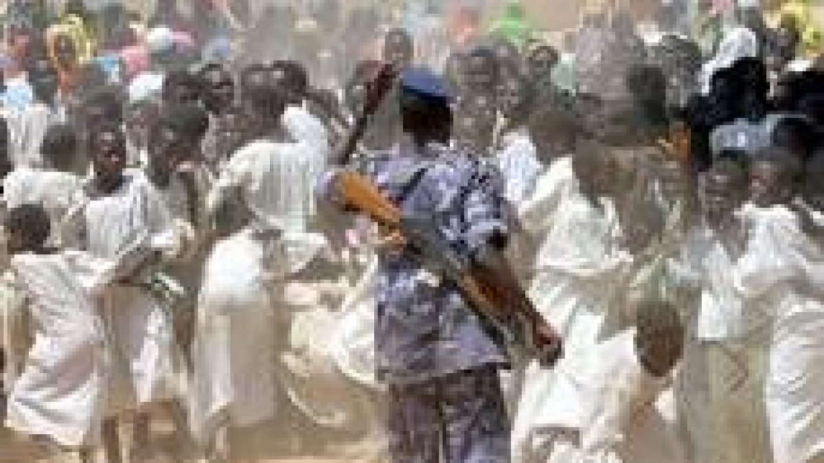 Un policía sudanés intenta controlar a la multitud en un campo de refugiados de Muhkjar
