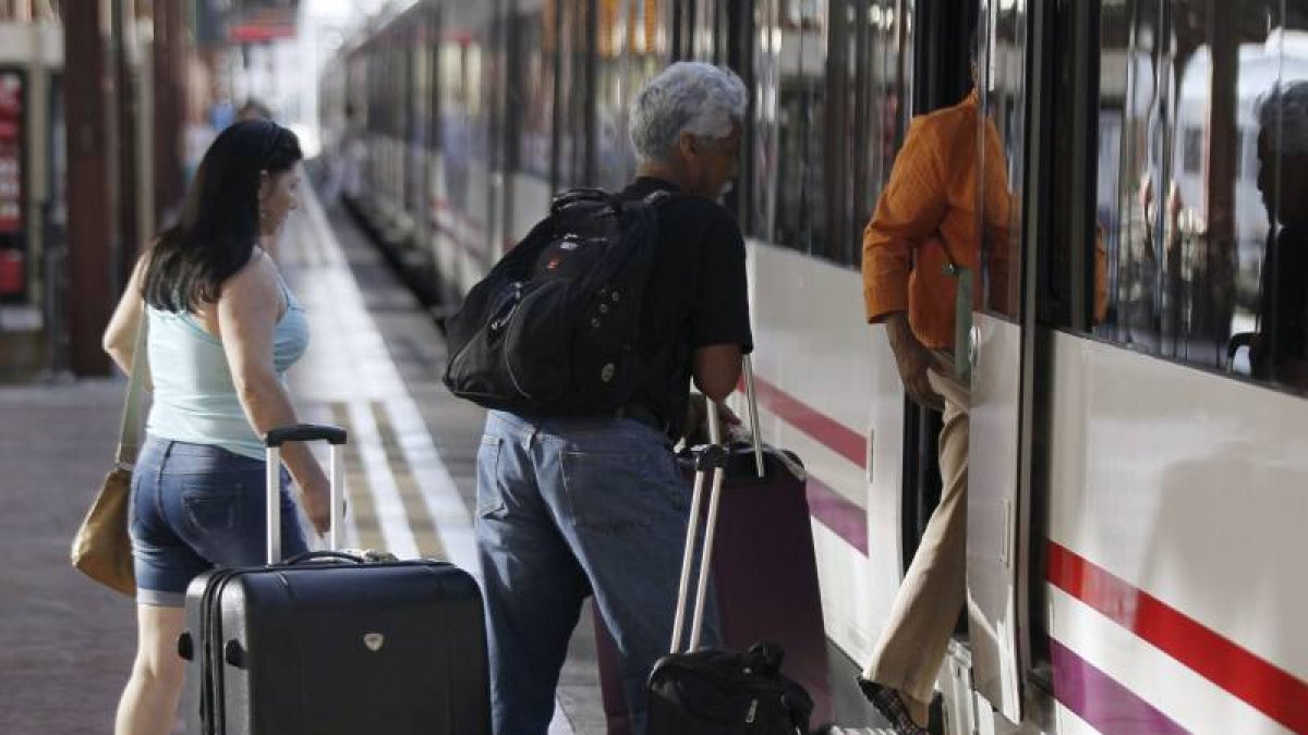 Varias personas montan a un tren esta mañana en la estación de Chamartín, en Madrid.