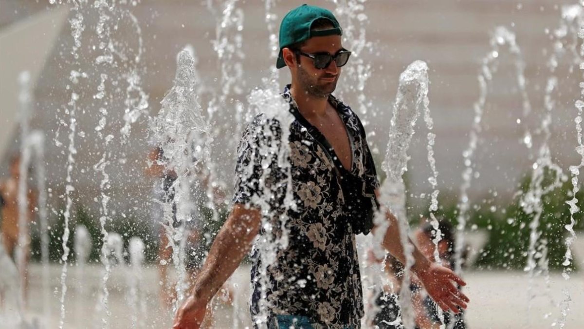 Un turista se refresca en una fuente de Lisboa.