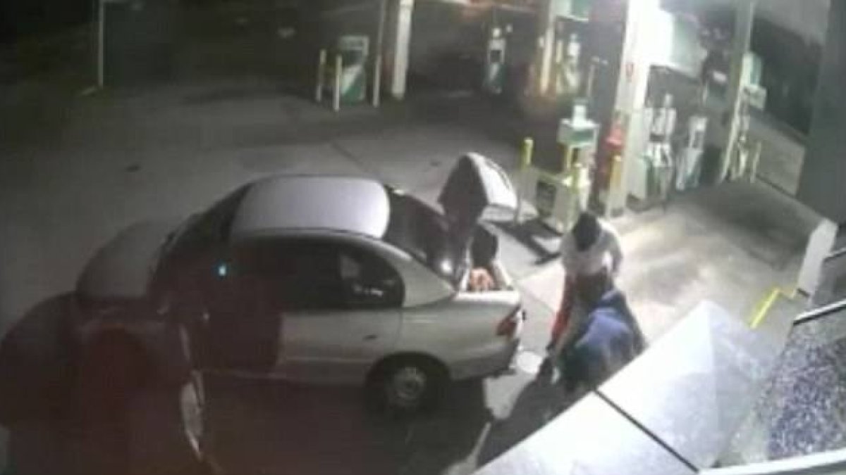Imagen de la grabación de una cámara de seguridad en que se ve como unos ladrones intentan llevarse un gran botín de tabaco en un saco tan grande que no les cabe en el coche.