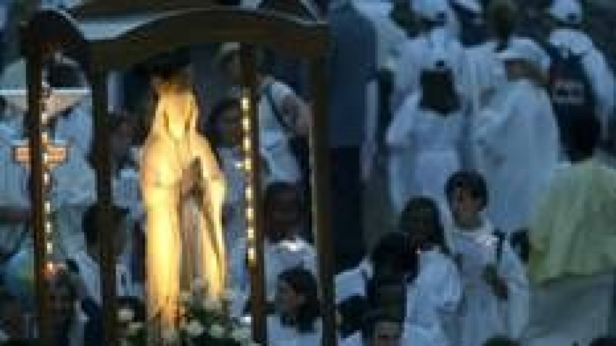 Una imagen de la virgen es llevada por los peregrinos durante una procesión nocturna en Lourdes