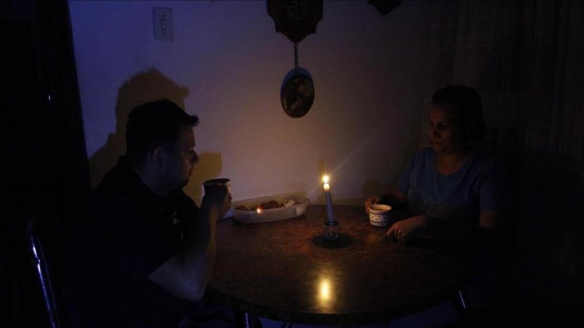 Una pareja toma un café en una establecimiento público a la luz de las velas.