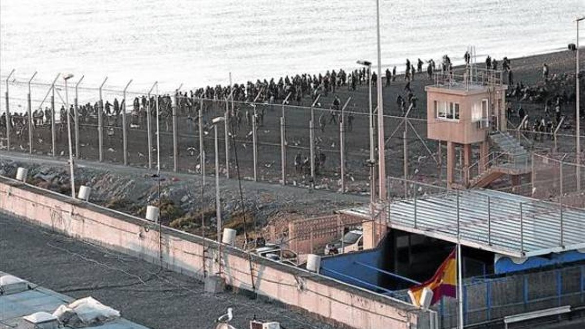 La policía marroquí impide el acceso de inmigrantes a la playa junto a la valla de Ceuta, en una imagen de archivo,