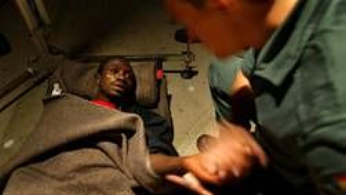 Un guardia civil sostiene la mano de uno de los africanos rescatado ayer cerca de Fuerteventura