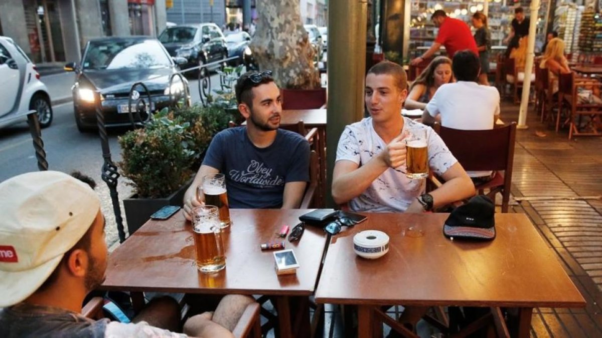 Unos turistas consumiendo jarras de cerveza en el centro de Barcelona.