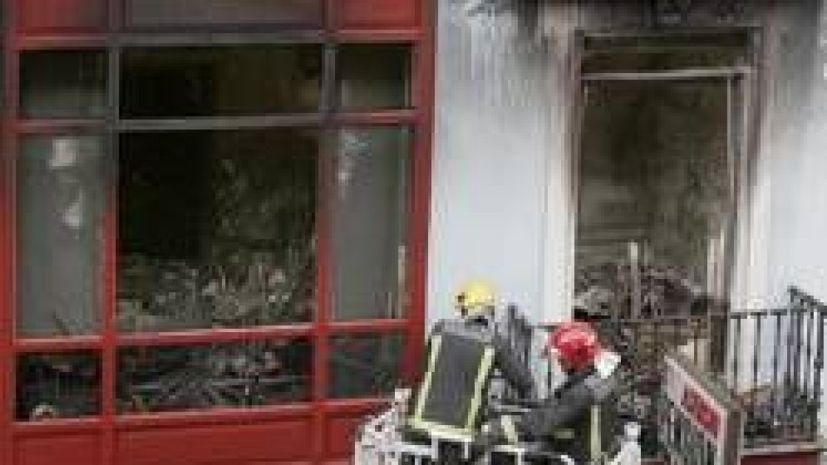 Unos bomberos retiran cascotes del inmueble incendiado
