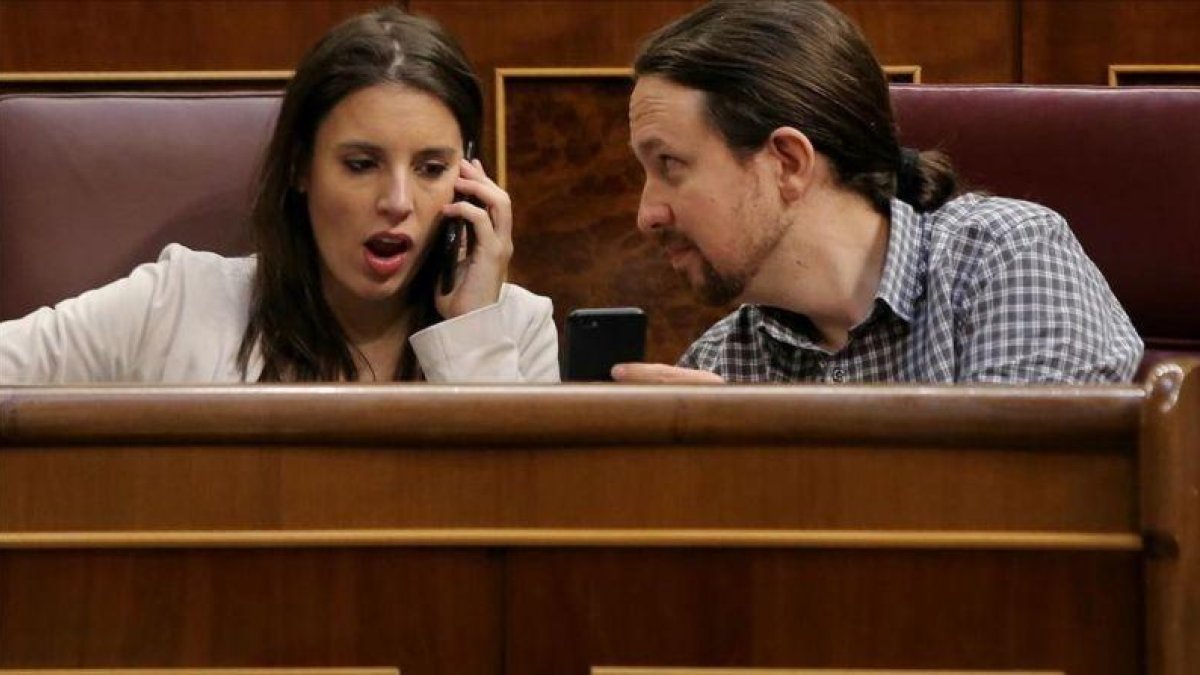 Pablo Iglesias muestra el móvil a Irene Montero durante el pleno en el Congreso.