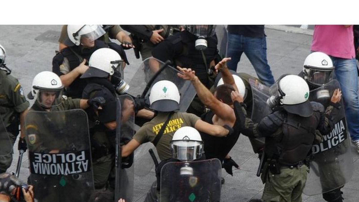 Policías golpean a un manifestante durante la manifestación de Atenas.