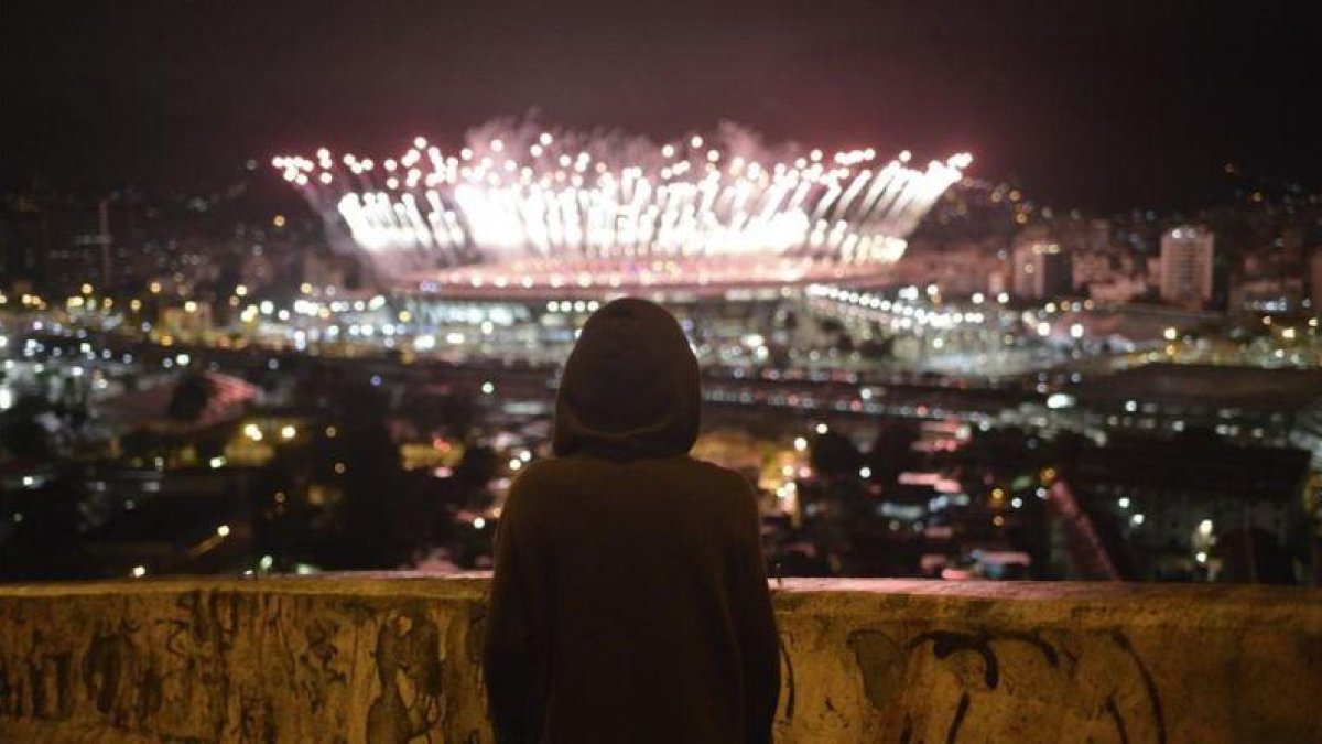 Un niño observa desde el Morro da Mangueira los fuegos artificiales de Maracaná durante la ceremonia de clausura de los Juegos, este domingo.