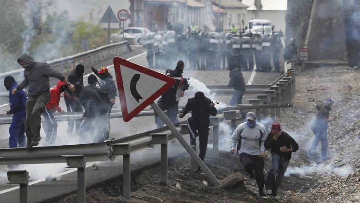 Los mineros corren al caer los botes de humo lanzados por los antidisturbios, a la entrada de Ciñera.