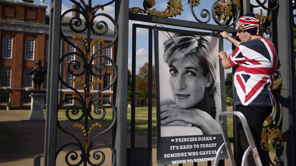 John Loughrey, seguidor de Diana, cuelga un cartel en las puertas del Palacio de Kensington en Londres. TOLGA AKMEN