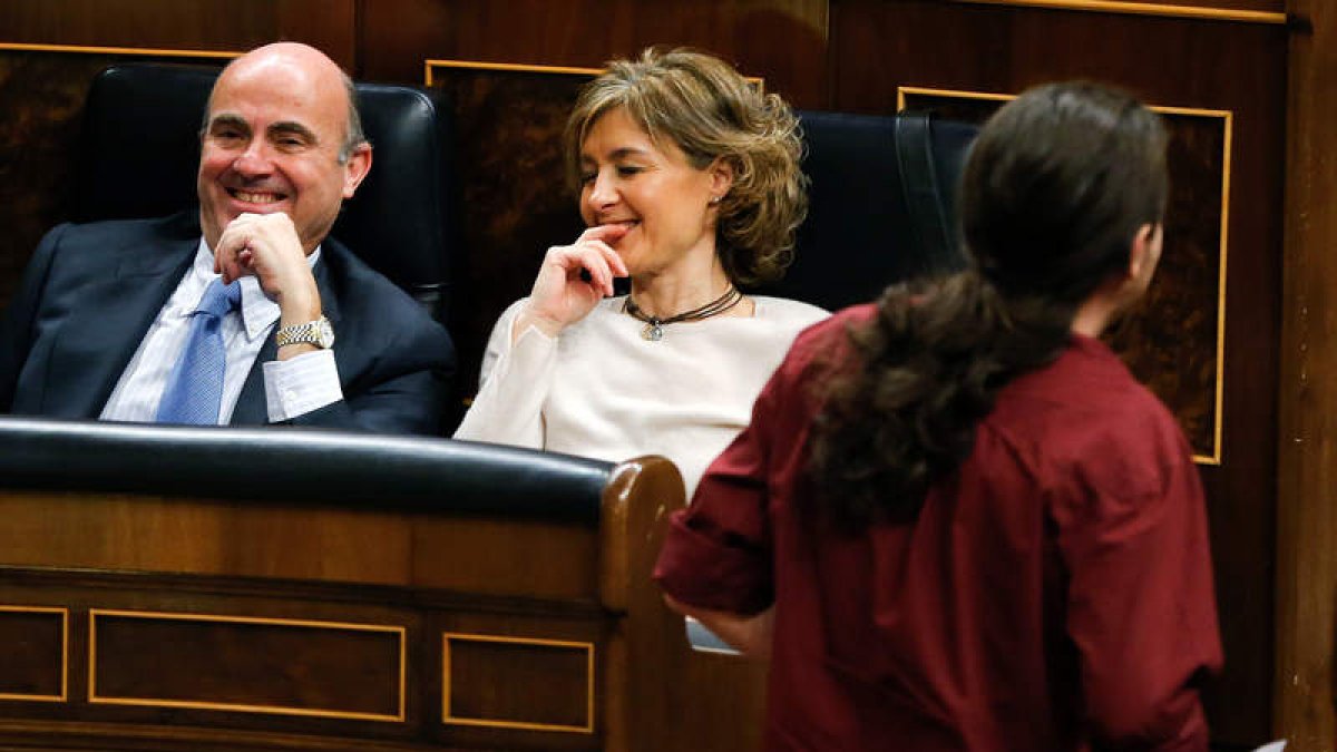 Luis de Guindos e Isabel García Tejerina sonríen mientras pasa a su lado Pablo Iglesias. BALLESTEROS