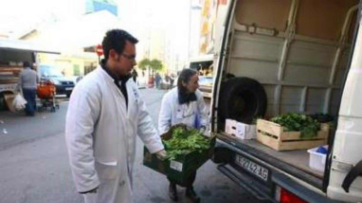 Dos voluntarios del Banco de Alimentos cargando la verdura en el furgón