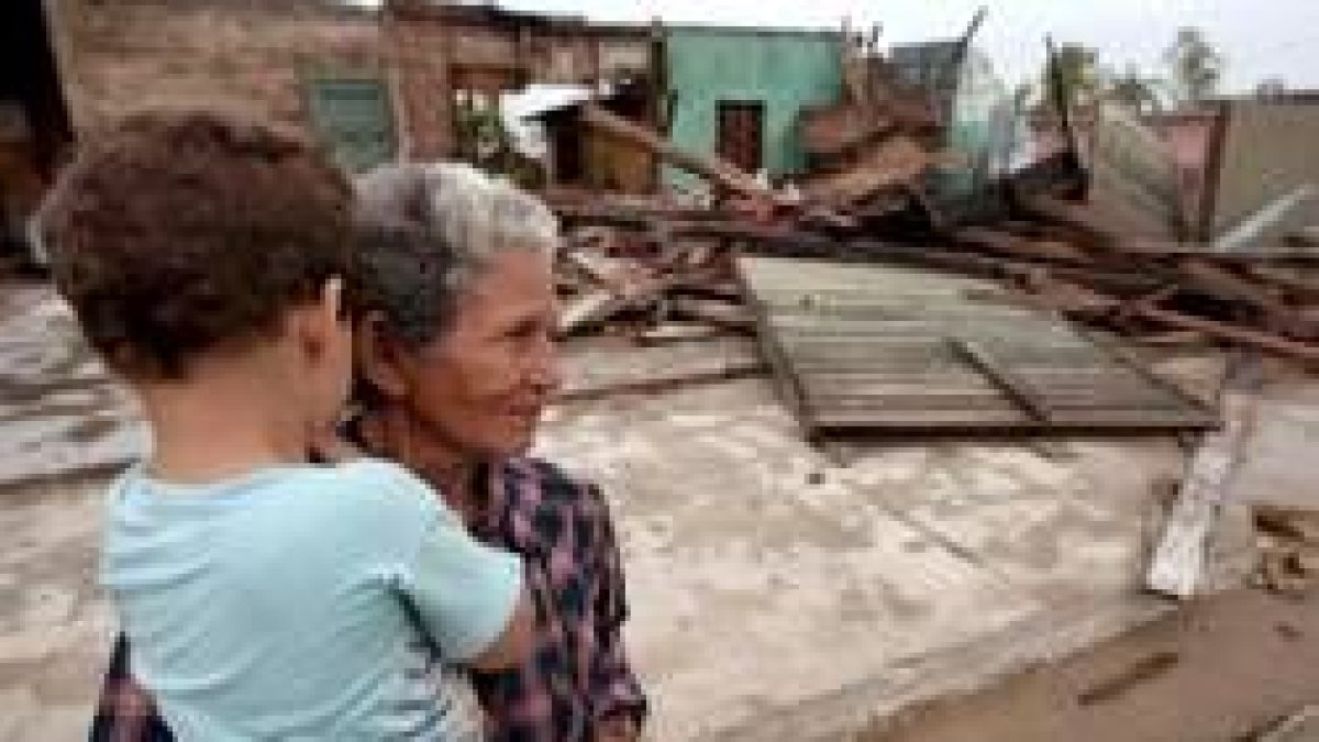 Una mujer cubana, sosteniendo a su nieto, contempla los destrozos que ha causado el huracán