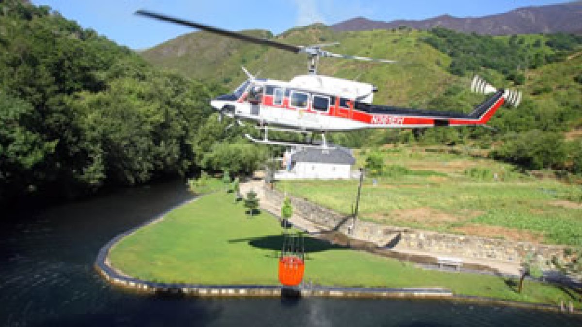 Un helicóptero recoge agua durante las tareas de extinción del incendio forestal