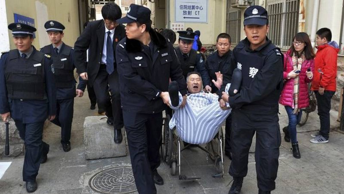 Varios policías sacan a rastras a Chen del hospital.