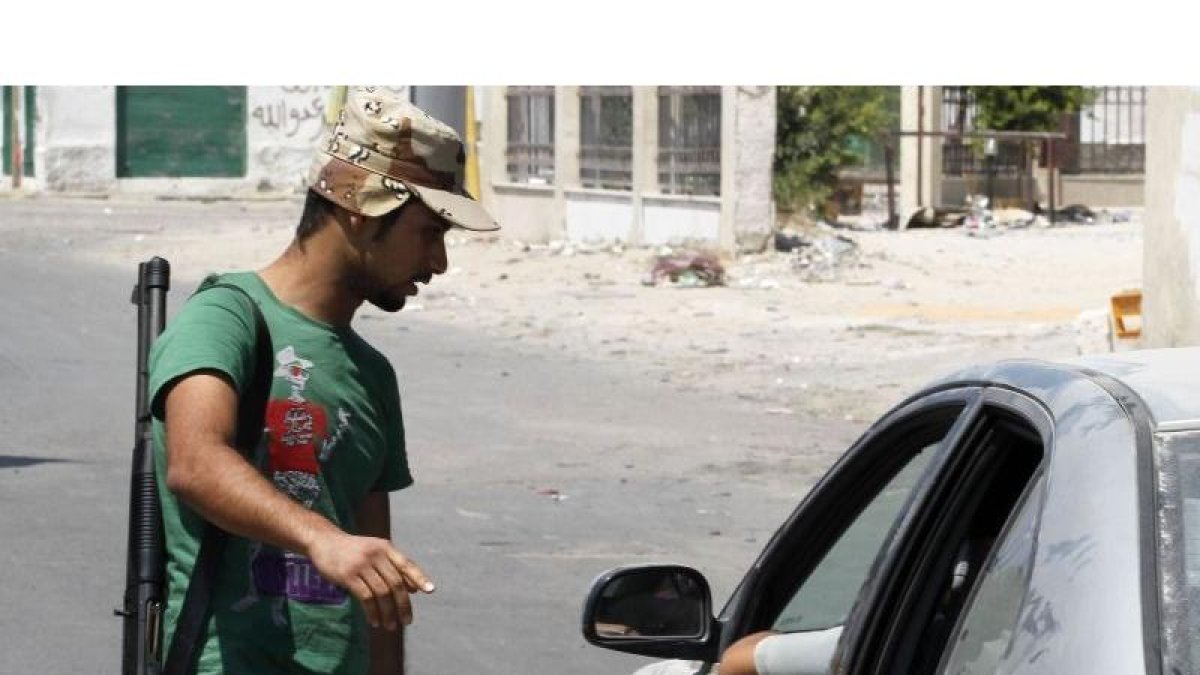 Un rebelde para un coche en uno de los controles de las calles de Trípoli, hoy.