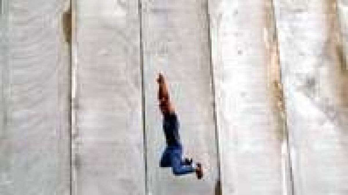 Un joven palestino salta en el «muro de la vergüeza» que levanta Sharon