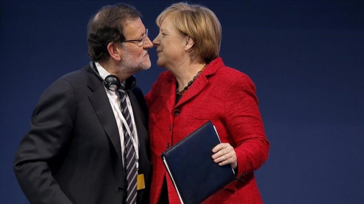 Rajoy y Merkel se saludan durante un congreso del Partido Popular Europeo.