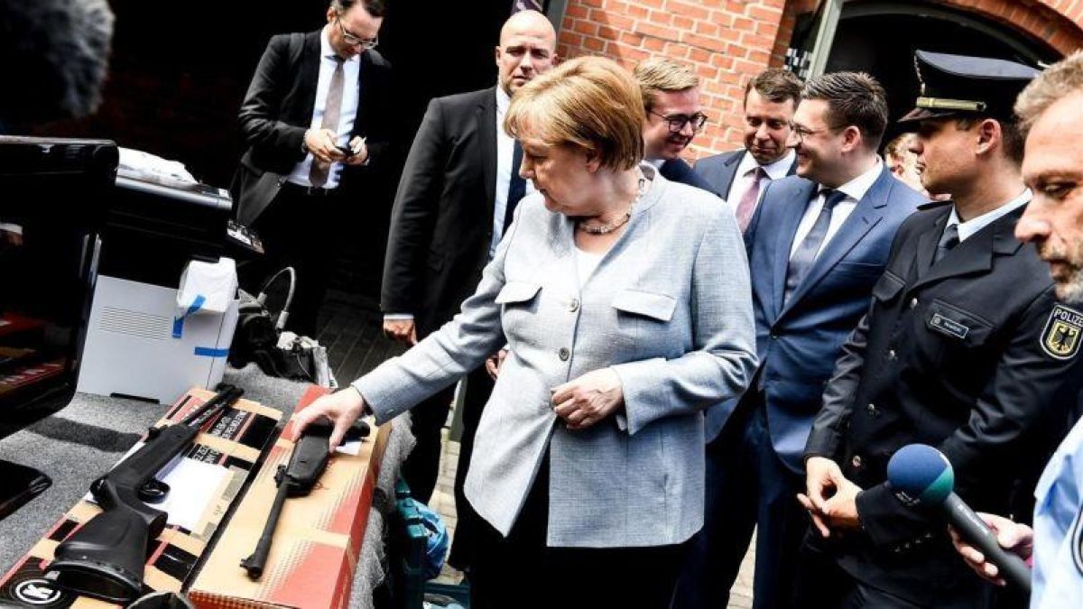 La cancillera alemana Angela Merkel observa armas de fuego durante su visita al Departamento Federal de la Policía en Pasewalk.