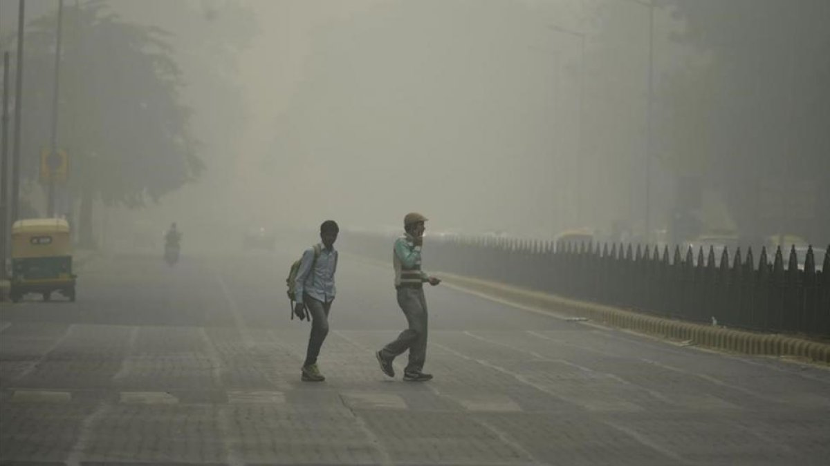 Peatones en medio de una intensa niebla toxica en Nueva Delhi.