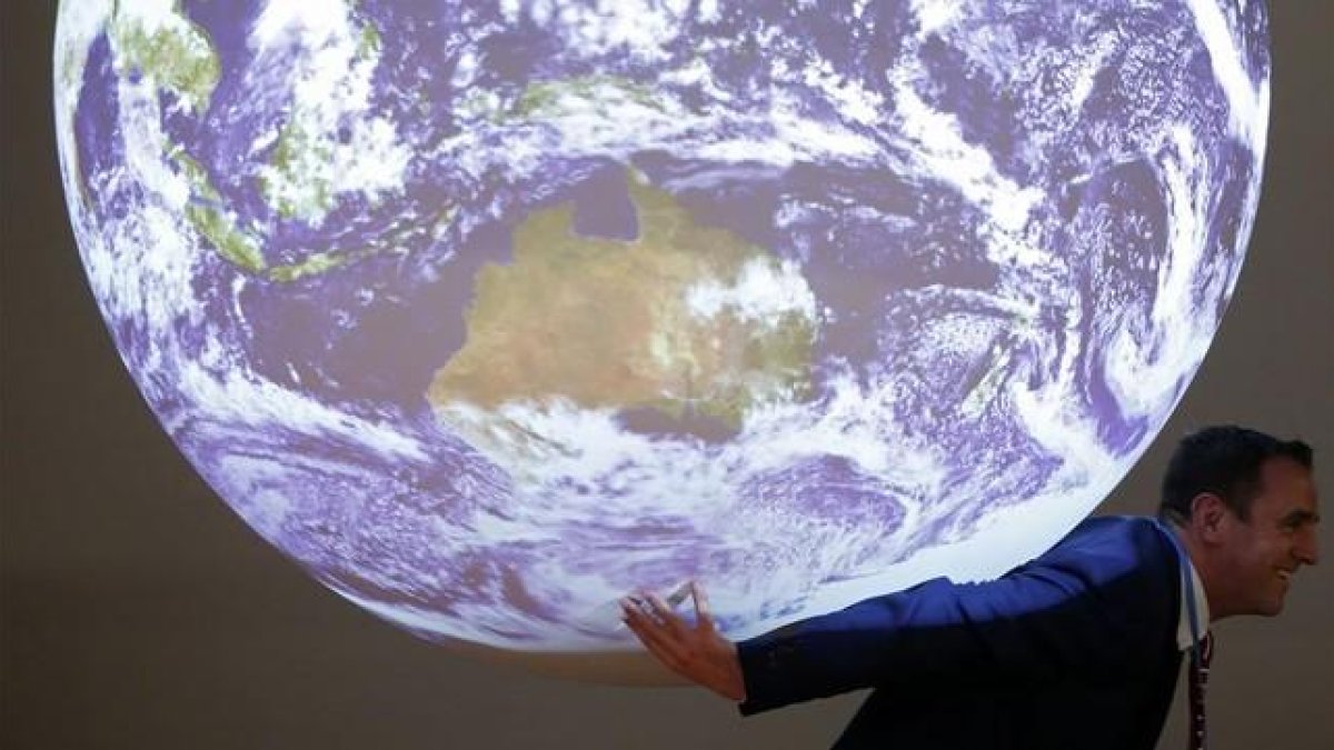 Un participante en la cumbre del clima posa ante la bola del mundo que se exhibe en el encuentro
