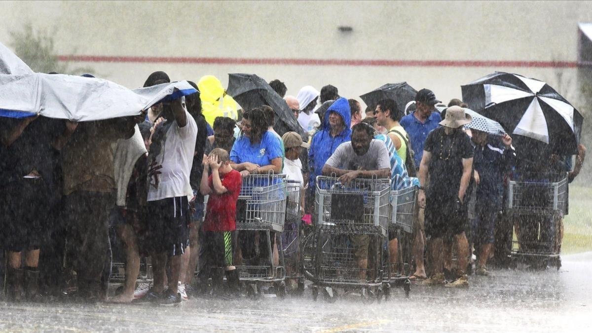 Un grupo de personas hace cola bajo una intensa lluvia en una tienda de ultramarinos en Carolina del Norte.
