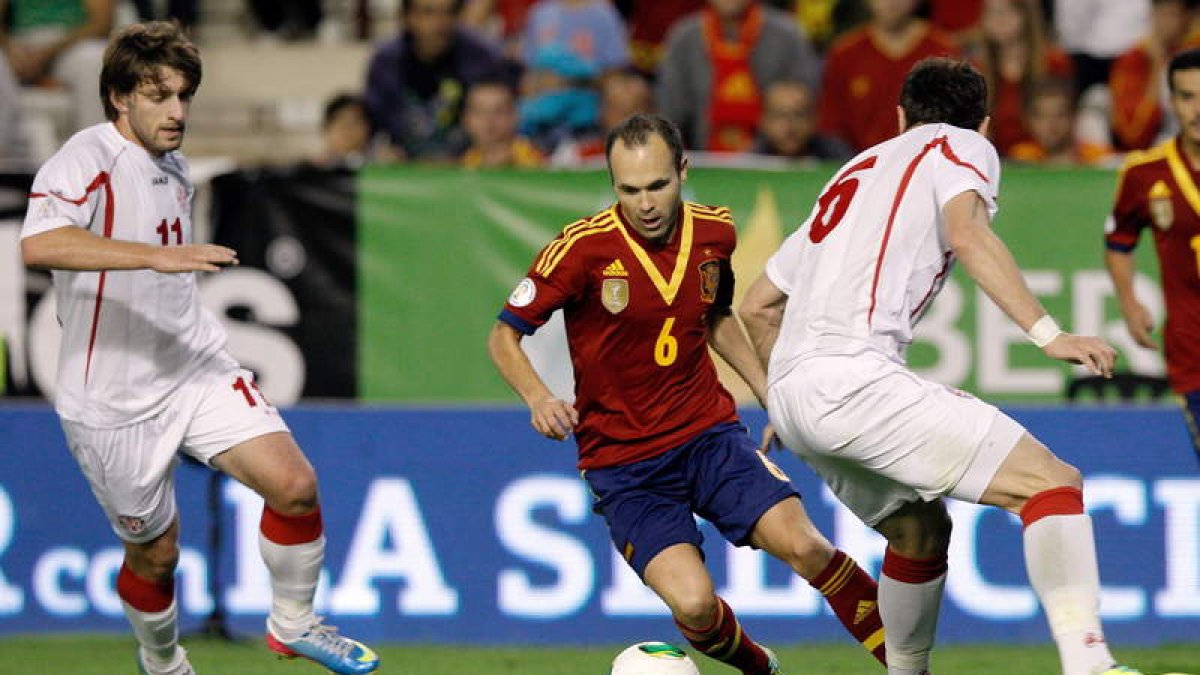Andrés Iniesta controla el balón ante los jugadores de Georgia, Tornike Okriashvili, izquierda, y Akaki Khubutia, durante el partido clasificatorio para el Mundial.