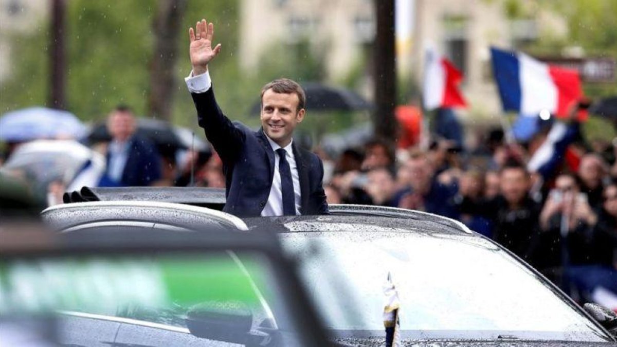 Macron saluda a la multitud desde su coche presidencial en París.
